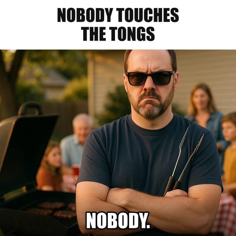 A serious dad in sunglasses standing guard in front of a backyard grill like a bodyguard, arms crossed, holding barbecue tongs, family party blurred behind him. Caption: "Nobody touches the tongs Nobody."